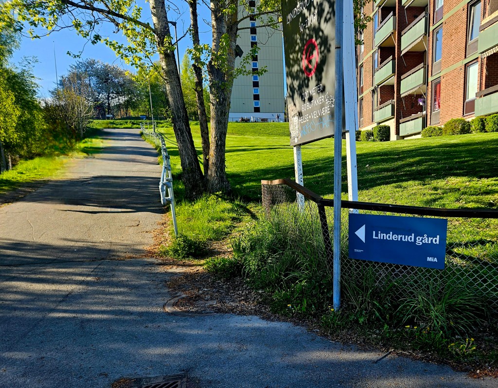en sti midt i bildet, og til høyre et skilt som sier Linderud gård.