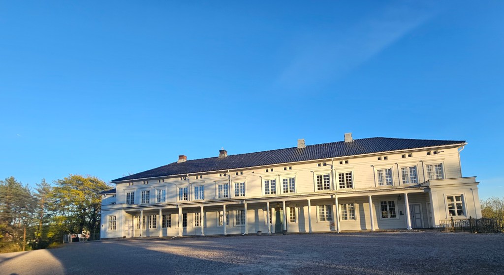 Bildet av hovedhuset på Linderud gård; en stor hvit bygning